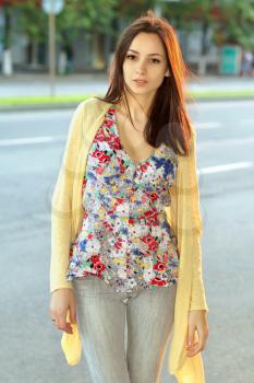 Pretty brunette in flowered blouse posing near the carriageway
