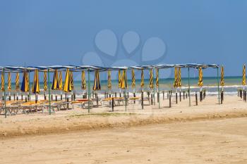 Rows of umbrellas and deck chairs on a sunny beach