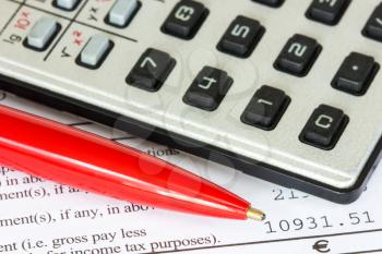 Calculator and red pen on the tax form