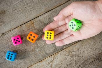 Hand throwing colorful dice  on the old wooden floor.
