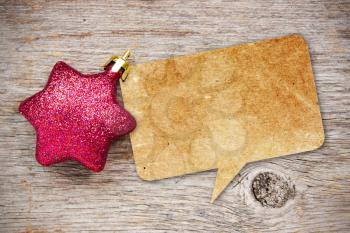 Blank recycled paper speech bubble with Christmas bauble on wood background 