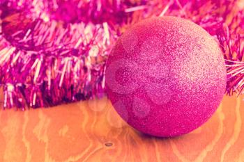 Purple bauble and tinsel on wooden background. Vintage effect.