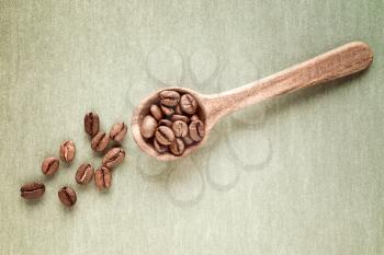 Spoon with coffee crop beans on paper background