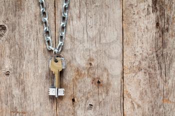 Keys hanging on chain against old  wooden wall