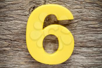 Yellow number six on the wooden background