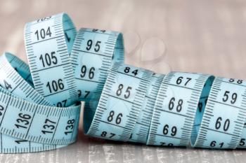 Blue measuring tape laying on grey wooden background