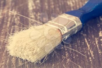 Close up of paint brush on a wooden background. Filtered image.
