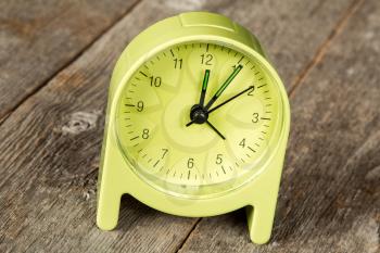 Green alarm clock showing five minute past twelve hour