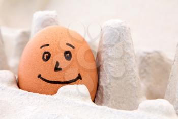 Smiling egg in a carton box, close up view