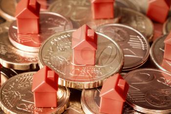 Close-up of mini houses resting on coins pile. Concept for property ladder, mortgage and real estate investment
