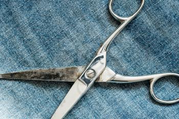 Metal scissors laying on the jeans background