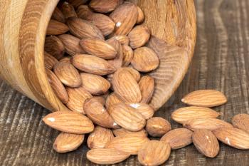 Peeled almonds in a wooden bowl on wooden background