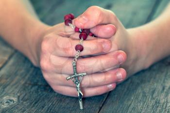 Childs hands holding catholic rosary. Child praying. Shallow DOF.
