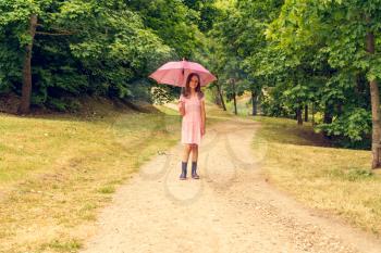 Child girl with umbrella walking in a park