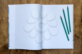 White blank pages sketchbook with pencils on wood table