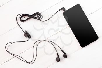 Smartphone with earphones  on wooden background