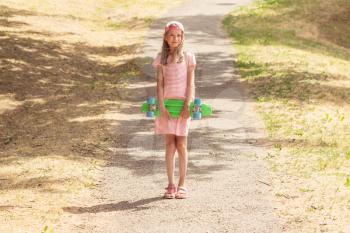 Little girl child with skate board on the park path