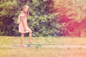 Little girl child with skateboard in a summer park
