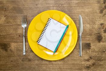 Yellow plate with open notebook for notes. Menu template