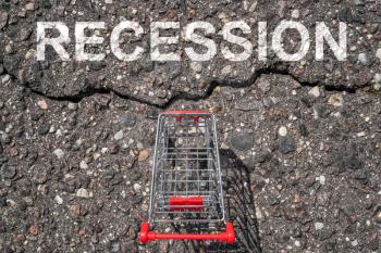 Asphalt crack between shopping cart and word  RECESSION. Economic crisis or recession concept