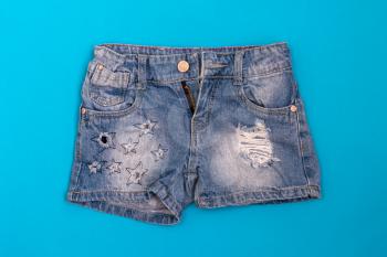 Ripped stylish jeans shorts on a blue background