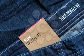 Size tag on blue jeans close-up. Men's slim jeans.