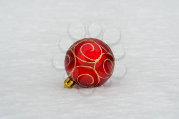 Red Christmas bauble lying in the snow