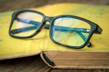 Old book with  glasses on a wooden table