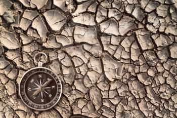 Top view of compass on the cracked dry soil. Ecological disaster concept.