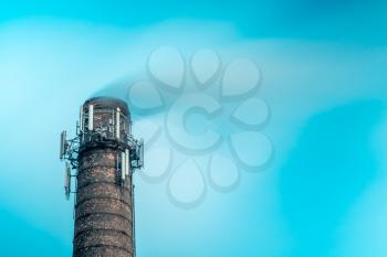 Top of high industrial chimney with multiple antennas. Factory chimney and steam in long exposure