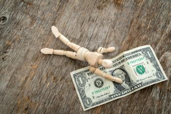 Wooden man reaches for the last dollar bill - running out of cash. Recession or economy crisis.