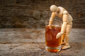 Alcohol addiction - wooden man holding a glass of whiskey