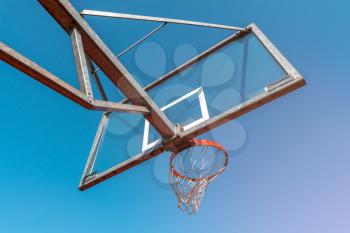 Bottom view of basketball hoop and clear blue sky. The concept of sports and a healthy lifestyle