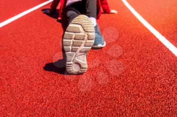 Girl sit on the running track in stadium, rest and relax after exercise concept.
