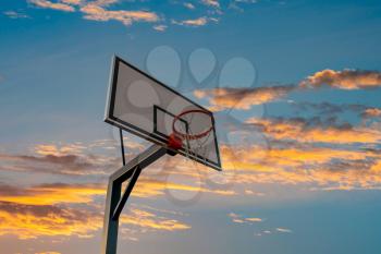 Basketball board with basket hoop against sunset sky. Sport, recreation.