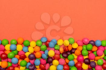 Many colorful candies on red background. Copy space.