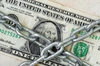 Closeup of US dollar under metallic chain. Corruption in USA. Financial safety, economic crisis, business investment, currency and money protection concept.