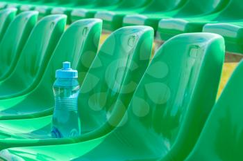 Water bottle on the green seats of outdoor sports ground