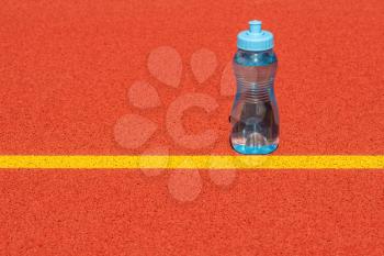 Sports water bottle stands on a run track start line