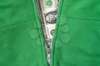 Close-up view of green sweatshirt with zipper and one dollar as background