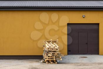 Wood Shipping Pallets Stacked Against Building Garage Door