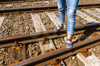 Woman standing on the railroad with summer sandals. Travel concept.