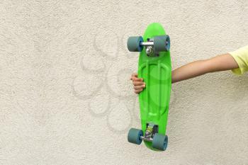 Youth culture. Hand with green penny board against  wall with empty space for text