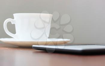 Mobile device and cup of coffee on wood table