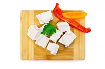 Slices of brine cheese, parsley, slices of red and yellow sweet peppers on a wooden board isolated on white background
