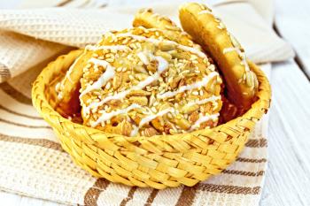 Biscuits with sesame seeds and sunflower and wicker bowl, napkin on a lighter background of the board