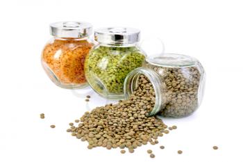 Lentils green, red, brown glass jars in a row isolated on white background