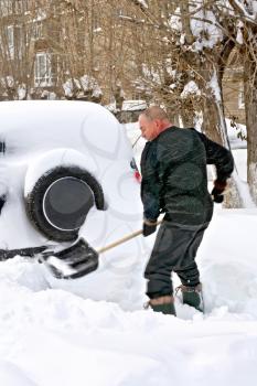 A man with a shovel digs up your car in the snow