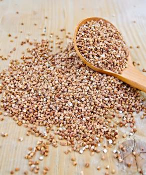 Buckwheat with a spoon on a wooden boards background