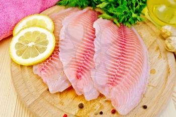 Tilapia fillets, dill, parsley, lemon, ginger, pink cloth, vegetable oil on a wooden boards background